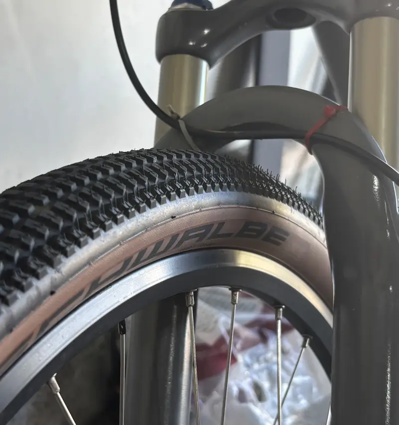 Close-up of a tan-wall Schwalbe gravel tire under a suspension fork.